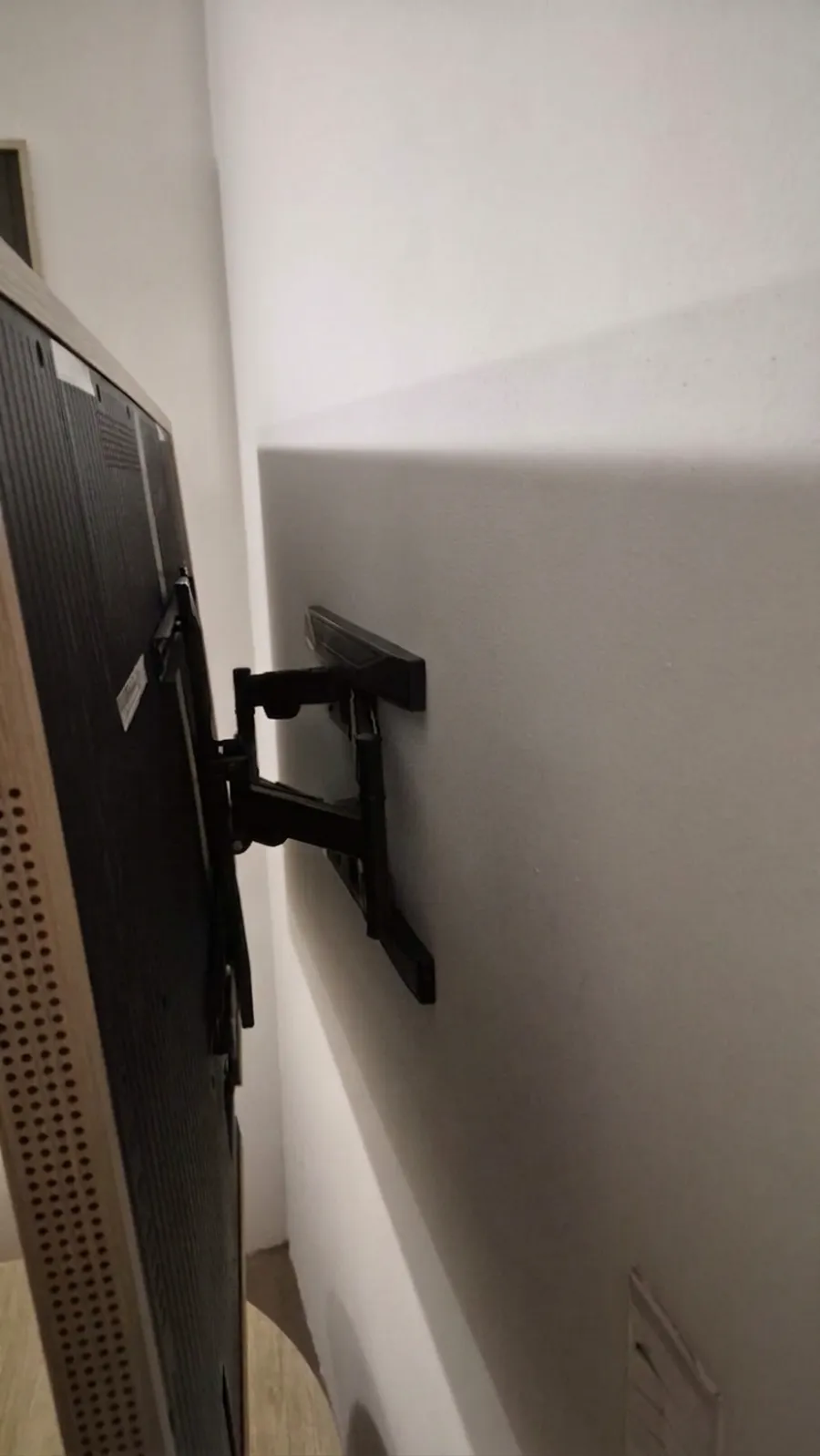 Soporte articulado instalado en pared de living, brazo extendido y nivelado